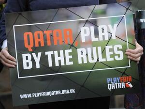 A demonstrator holds a placard critical of Qatar's policies regarding the working conditions of migrant workers in light of the increased construction to provide the infrastructure for the Gulf state to host the FIFA World Cup in 2022. AFP PHOTO / ANDY BUCHANAN
Andy Buchanan / AFP
