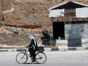 SYRIA, QUSAYR : A Syrian resident rides his bicycle on August 1, 2013 in a street of the city of Qusayr, in Syria's central Homs province. AFP PHOTO/JOSEPH EID