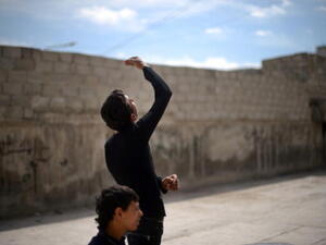 A Syrian young man looks up as a government forces fighter jet flies overhead in the northern Syrian city of Aleppo on April 15, 2013. ( DIMITAR DILKOFF/AFP/Getty Images)