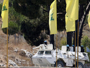 LEBANON, MARJAYOUN : Spanish peacekeepers of the United Nations Interim Force in Lebanon (UNIFIL) patrol in their armoured vehicles near a placard of Hezbollah on July 23, 2013 in the southern Lebanese city of Marjayoun. AFP PHOTO MAHMOUD ZAYYAT