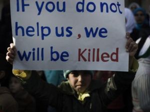 طفل سوري يحمل لافتة في مظاهرة ببلدة القصير،جنوب شرق حمص، كتب عليها :إن لم تساعدوننا فسوف نقتل/أ.ف.ب
