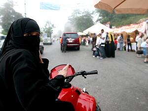 A veiled woman takes her motor bike for a spin.  Though women are banned from driving in his home country, Saudi Prince Fahad al-Saud has developed "Saudi Girls Revolution," a post-apocalyptic action game featuring female bikers.  (AFP/Joseph Barrak)