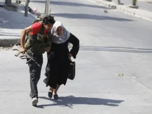مقاتل من المعارضة يساعد عجوز على عبور شارع في حلب/ارشيف