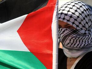 فلسطينية ترفع العلم الوطني بالقرب من حاجز اسرائيلي خلال تظاهرة احتجاج ضد العدوان على غزة في نابلس بالضفة الغربية/أ.ف.ب