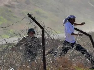 مواطن سوري يحاول الهرب في تجاه تركيا في حين يتصدى له جندي تركي/أ.ف.ب