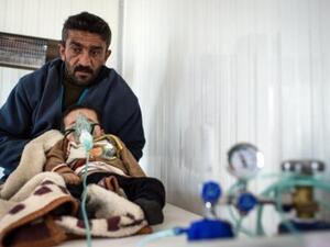 سوري مشرد يصطحب ابنه المريض الى عيادة صحية في مخيم اعزاز/شمال سوريا/أ.ف.ب