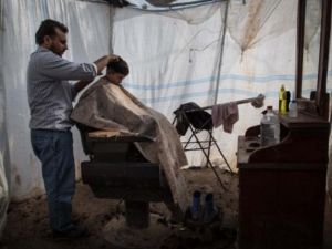 طفل سوري يقص شعره في محل حلاقة بمخيم اعزاز شمال سوريا/أ.ف.ب