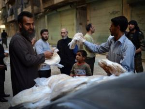 سوري يوزع الخبز في حي الشيخ مقصود بحلب/أ.ف.ب