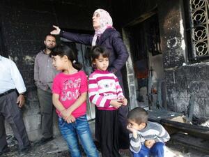 Palestinian family shows damage to their home after unknown assailant set it on fire, Thursday, November 14, 2013. [Haaretz.com]