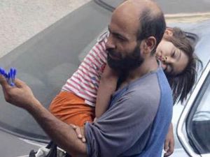 اللاجىء عبدالحليم العطار يحمل ابنته على كتفه خلال بيعه للأقلام