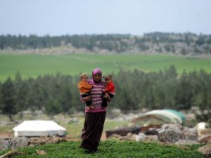 سورية لاجئة تحمل طفليها في مخيم قرب عفرين شمال سوريا/أ.ف.ب