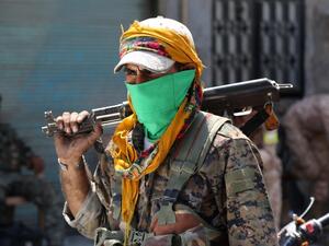 A member of the Syrian Democratic Forces (SDF) walks on a street with his weapon in the northern Syrian town of Manbij on August 7, 2016. (AFP/Delil Souleiman)