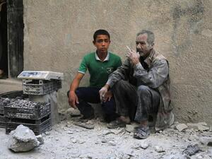 A man covered with dust sits on a street following a reported airstrike by Syrian government forces in the rebel-held neighborhood of Sukkari in Aleppo on May 30, 2016. (AFP/Baraa al-Halabi)