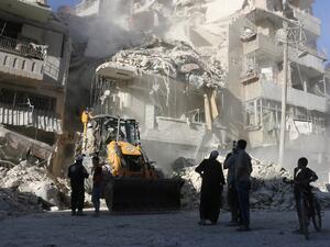 Civilians watch as a tractor clears the rubble following Syrian government forces airstrikes in the rebel held neighborhood of Tariq a-Bab in Aleppo on September 24, 2016. (AFP/Thaer Mohammed)