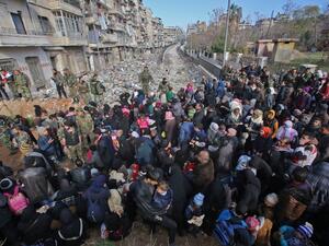 Syrian residents fleeing the violence gather at a checkpoint, manned by pro-government forces, in the Maysaloun neighborhood of the northern city of Aleppo on December 8, 2016. (AFP/Youssef Karwashan)
