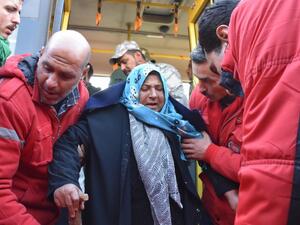A woman is assisted by members of the Syrian Arab Red Crescent after two buses evacuated civilians from Fuaa and Kafraya, two Shia villages under rebel-siege near Idlib, on December 19, 2016. (AFP/George Ourfalian)