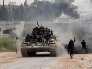 Fighters from a coalition of Islamist forces celebrate after taking the al-Mastumah base in the Syrian city of Idlib (AFP/ File)
