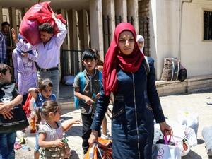 Syrian refugees asnd children walk with their belongings as they prepare to board a bus at the Masnaa crossing on the Lebanon-Syria border on July 28, 2018, returning them back to Syria. (AFP/ Photo)
