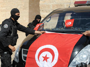 Tunisian Police Special Unit agents fix a national flag on their vehicle in front of the Okba Ibn Nafaa mosque in the central Tunisian city of Kairouan. (Fethi Belaid/ AFP)
