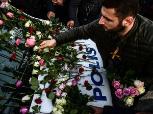 A man lays flowers on a police vehicle as people pay their respects outside the Vodafone Arena football stadium in Istanbul on December 11, 2016, a day after twin bombings near the home stadium of Besiktas football club. (AFP/Yasin Akgul)