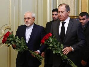 Russian Foreign Minister Sergei Lavrov (R) and his Iranian counterpart Mohammad Javad Zarif lay flowers in front of a photo of Russian ambassador to Turkey, who was killed in Ankara, before their talks in Moscow on December 20, 2016. (AFP/Maxim Shemetov)