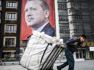 A man pulls a cart in front of a huge portrait of Turkish President Recep Tayyip Erdogan on Taksim Square in Istanbul on March 15, 2017. (AFP/Bulent Kilic)