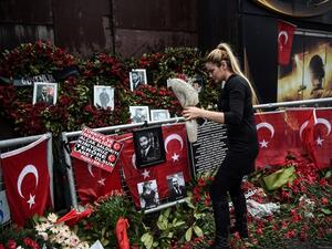 A woman lays flowers by a makeshift memorial in front of the Reina nightclub in Istanbul on January 17, 2017, a day after Turkish police arrested the suspected attacker. (AFP/Ozan Kose)