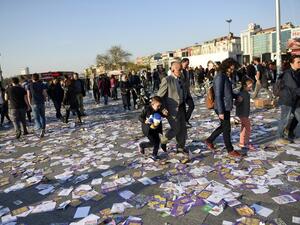 A man and a woman hold each other a child by the hand as they walk on leaflets reading "yes" thrown on the ground at the Kadikoy district, in Istanbul, after the start of the election banning, on April 15, 2017, on the eve of the constitutional referendum. (AFP/Bulent Kilic)