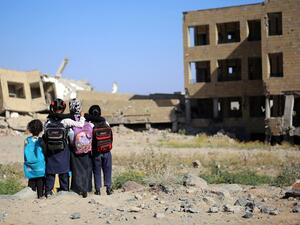 Yemeni school girls look at a school on March 16, 2017, that was damaged in an air strike in the southern Yemeni city of Taez. (AFP/Ahmad al-Basha)