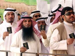 KUWAIT, KUWAIT CITY : Kuwaiti men display their identity cards as they wait to cast their votes at a polling station in Kuwait City on July 27, 2013. AFP PHOTO/YASSER AL-ZAYYAT