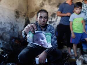 A family member holds up a photo of Ali Dawabsheh, a Palestinian toddler killed last week by Israeli settlers in an arson attack on his home.  (AFP/Majdi Mohammed)