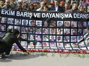 A wonam lays red carnations as people hold a banner with pictures of victims of October 10 bombings during a memorial ceremony in Ankara on April 10, 2016. (AFP/Adem Altan) A wonam lays red carnations as people hold a banner with pictures of victims of October 10 bombings during a memorial ceremony in Ankara on April 10, 2016. (AFP/Adem Altan)