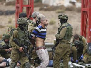 جنود اسرائيليون يعتقلون فلسطينيا بينما يستلقي فلسطينيان اخران مصابان على الارض تحت سيطرة الجنود