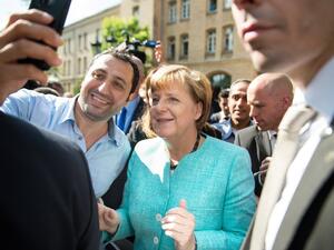 An asylum seeker takes a selfie with German Chancellor Angela Merkel following her visit at a camp for asylum seekers in Berlin on Sept. 10, 2015. (AFP/Bernd Von Jutrczenkia)