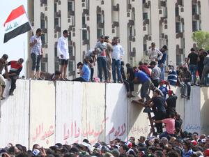 Iraqi protesters climb over a concrete wall surrounding the parliament (unseen) after breaking into Baghdad's heavily fortified "Green Zone" on April 30, 2016. (AFP/Haidar Mohammed Ali)