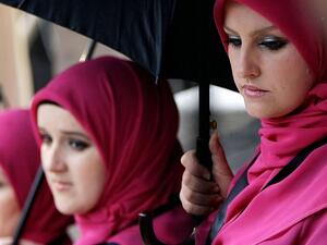 Bosnia has become a favored destination for Arab tourists and investors alike.  In the photo: Bosnian women take cover from the rain under umbrellas in Sarajevo, on January 15, 2014. (AFP)