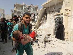 An medical worker carries a wounded child in Aleppo, Syria.  (AFP/Karam al-Masri)