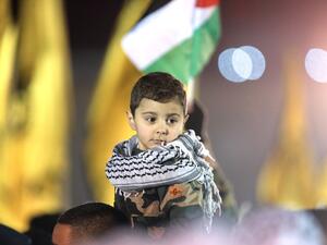 A Palestinian child watches a parade of Palestinian Fatah movement fighters during a rally marking the 50th anniversary of the movement's creation on December 31, 2014. (AFP/Abbas Momani)