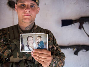 A 26-year-old from the US, nicknamed Hewal Dilsad by Kurdish fighters in northwestern Syria, displays a photograph of his wife and son.  (AFP/Uygar Onder Simsek)
