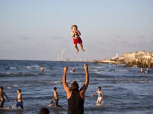 In a moment of calm following 2014's brutal war in Gaza, a man throws his laughing baby into the air on the beach in Gaza City.  Gaza's beaches, where last summer four boys were killed by Israeli missiles while playing soccer, are worlds away from the swanky seaside hangouts of Tel Aviv.  (AFP/Mahmud Hams)
