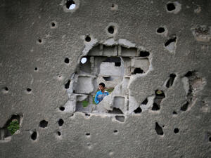 A Palestinian boy stands behind a bullet-ridden wall in Gaza City, destroyed during 2014's month-long war between Israel and Hamas militants, which devastated Gaza's civilians. (AFP/Mohammed Abed)