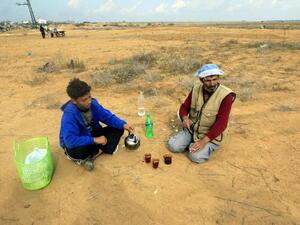 مزارع فلسطيني يحتسي الشاي مع ابنه خلال استراحة من العمل في الارض/أ.ف.ب