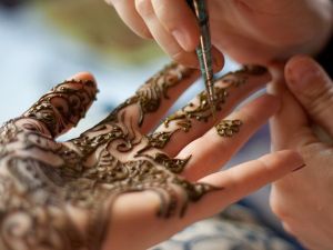 A woman getting a henna ink design applied to her hand. (Shutterstock)