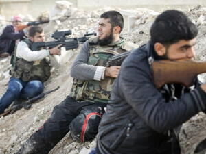 Rebels line a dirt escarpment as they look towards Syrian army positions south of the highway town of Maraat al-Numan on November 17, 2012. [Getty Images]