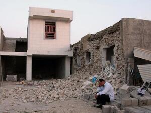 A man squats outside his destroyed home in Shonbeh, after the Bushehr earthquake (AFP)