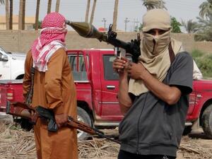 Iraqi armed tribesmen pose for a picture in front of a truck in a road north of Ramadi (Azhar Shallal/AFP)