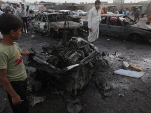 Iraqis gather at the scene of one of the two car bombs that exploded near an used car dealerships in Baghdad's Habibiyah area on May 27(Ahmad Al-Rubaye/ AFP)