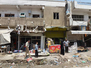 Iraqis inspect the damage outside shops in Baghdad on June 25, 2013 following an explosion the night before (Sabah Arar / AFP)