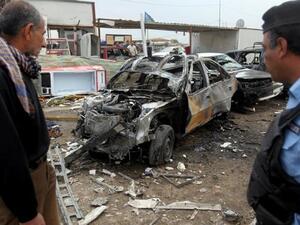 An Iraqi policeman and civilian inspect the wreckage of a car bomb in Baghdad on April 15 (AFP/ Ahmad Al Rubaye)