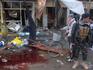 جندي عراقي يقف الى جانب بركة من دماء ضحايا تفجير في طوزخرماتو/أ.ف.ب